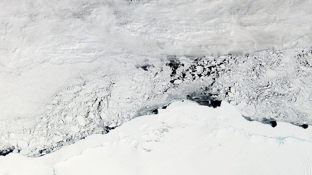 Satellite view of the Enderby Land coast in East Antarctica: the white ice sheet along the bottom, broken sea ice offshore and bands of cloud over the ocean beyond.