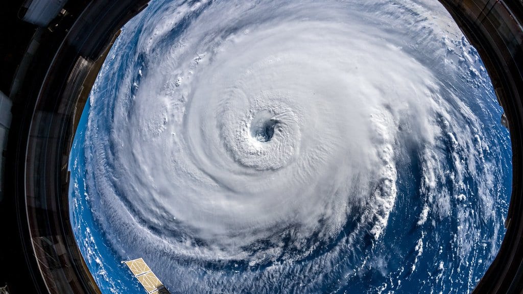 The eye of Hurricane Florence seen from the International Space Station, a vast white spiral of cloud over dark blue ocean, framed by the station's cupola window.