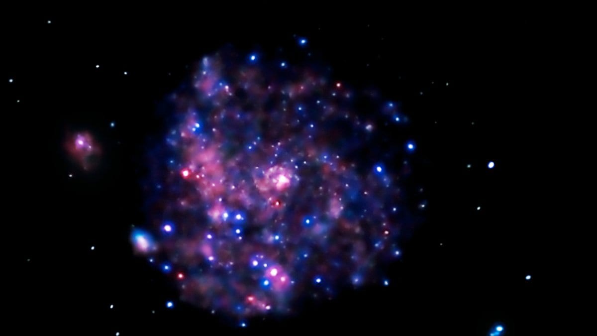 X-ray image of the Pinwheel galaxy showing a round blue and pink glow scattered with bright point sources against a black sky