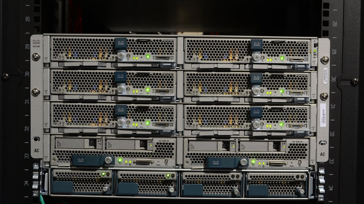 Front of a Cisco Unified Computing System blade server chassis mounted in a black equipment rack, rows of status lights lit green.