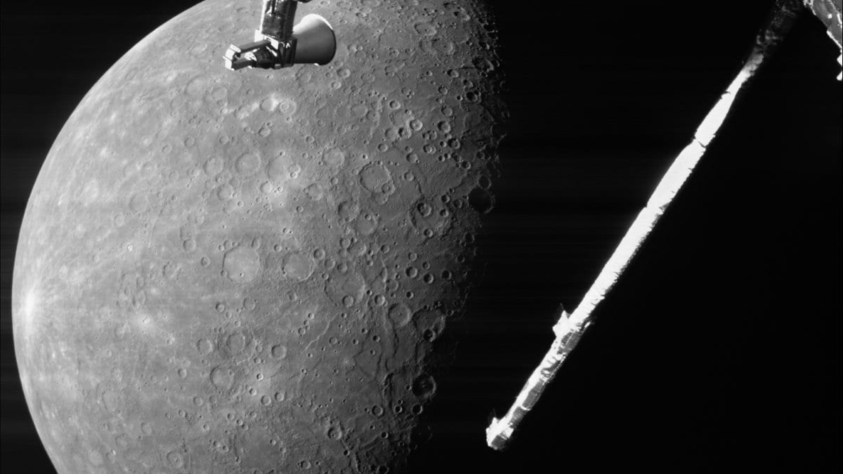 Black and white view of Mercury's heavily cratered surface filling the left of the frame, with a spacecraft boom and antenna crossing the dark sky at right.