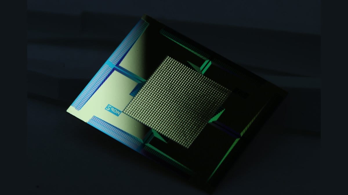 A small square chip carrying a dense grid of thousands of superconducting transition-edge sensor pixels, lit blue and green against a dark background.