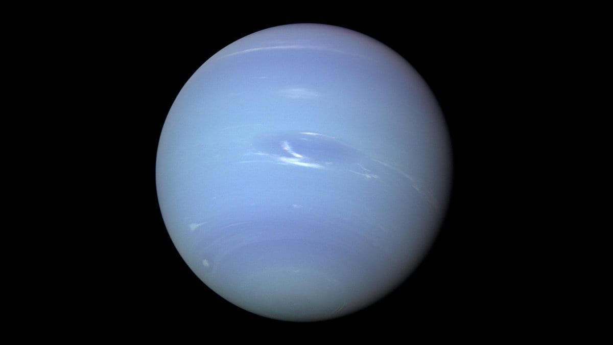 The full disk of Neptune, a pale blue planet with faint white cloud bands and a dark oval storm, against black space.