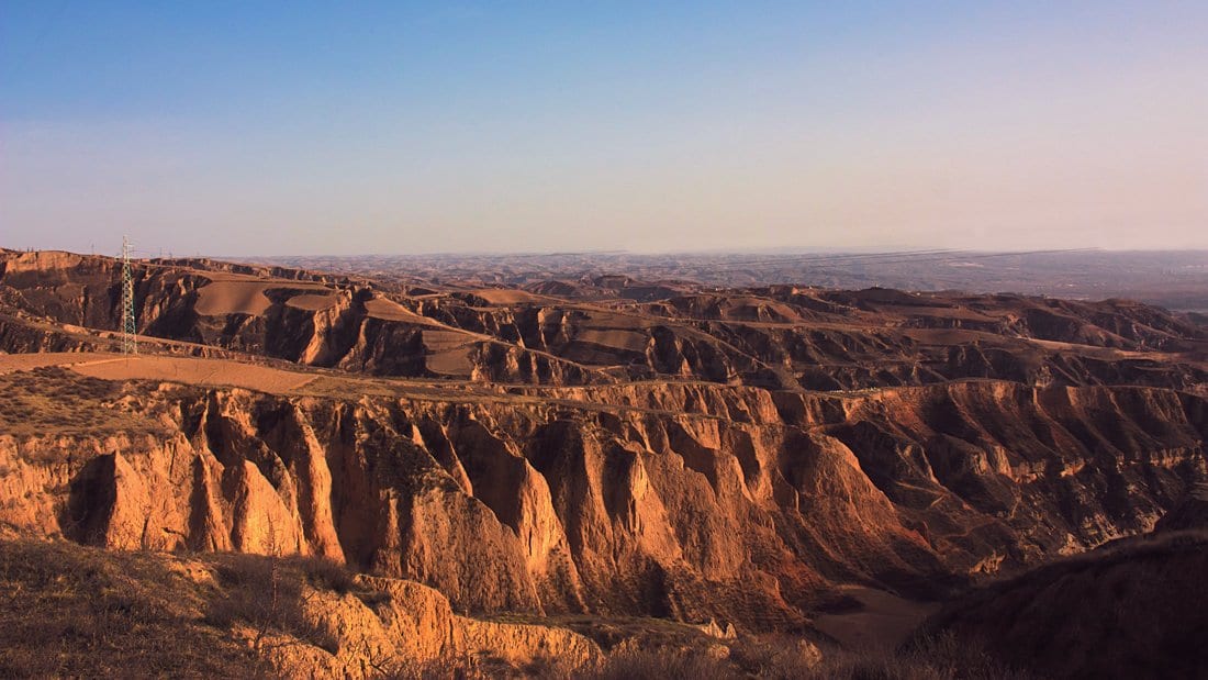 Gullies and terraces cut into thick wind-blown dust deposits on the Chinese Loess Plateau, lit by low sun.