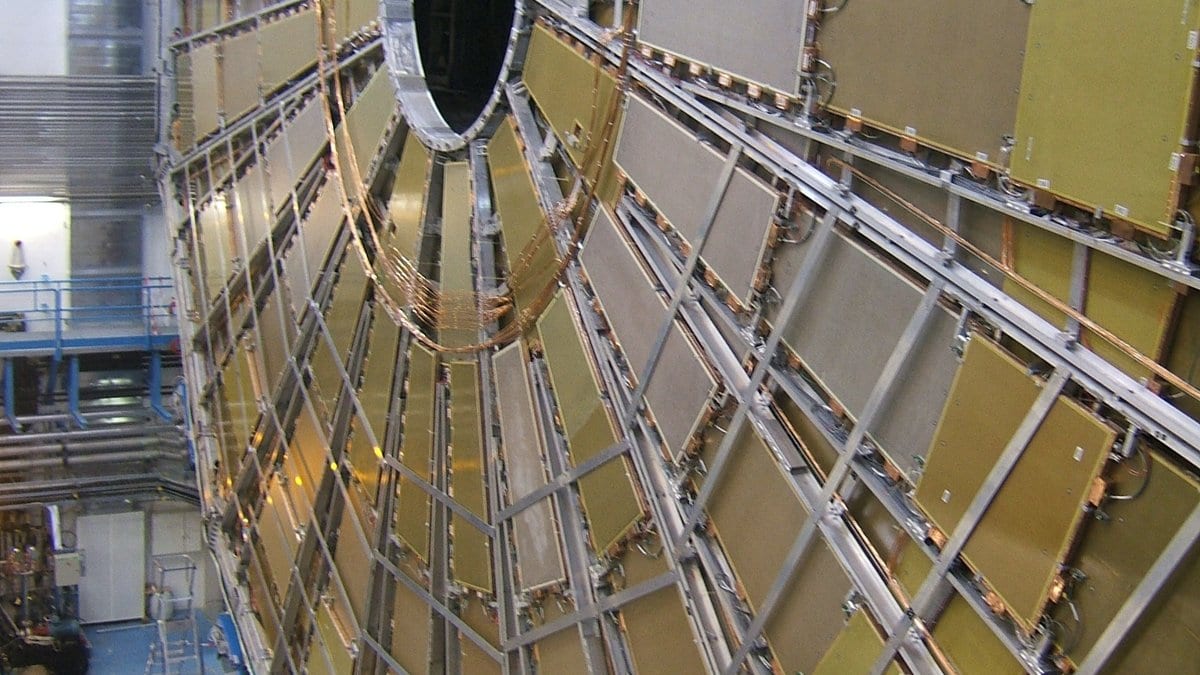 An end-cap wheel of muon detector chambers on the ATLAS experiment, with radial gold-colored panels around a central beam opening, during assembly in the underground cavern at CERN.