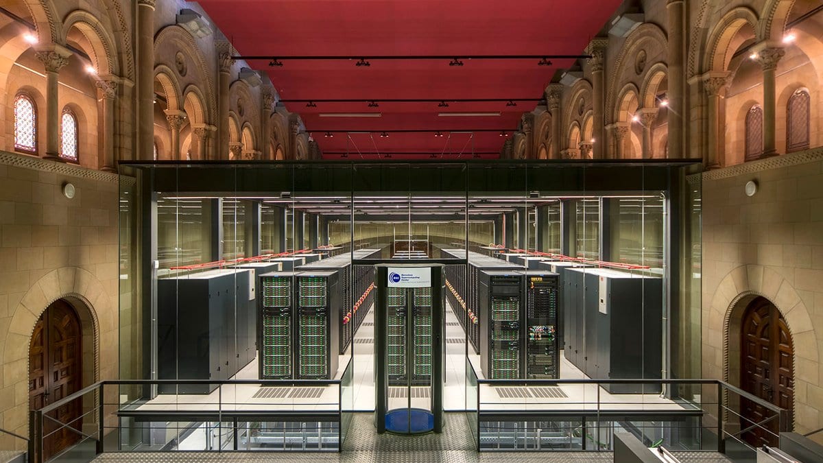 Rows of black computer racks inside a converted stone chapel at the Barcelona Supercomputing Center, seen from a raised walkway.