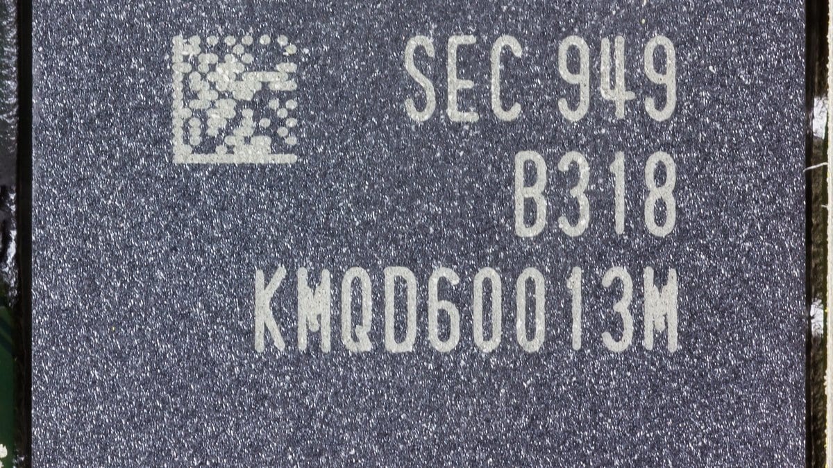 Close-up of a black Samsung mobile memory package soldered to a green smartphone circuit board, its laser-etched part number visible on the lid.