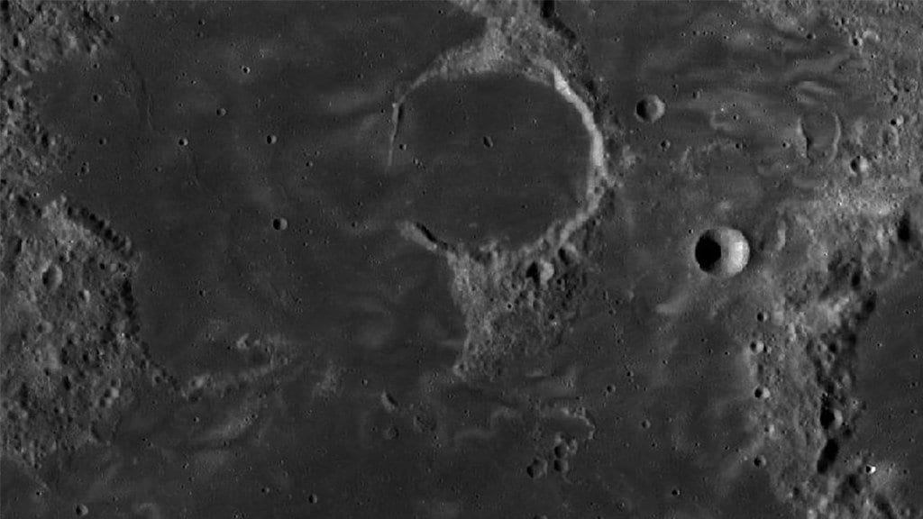 Bright, winding lunar swirl markings crossing a cratered lunar surface in an orbital image.