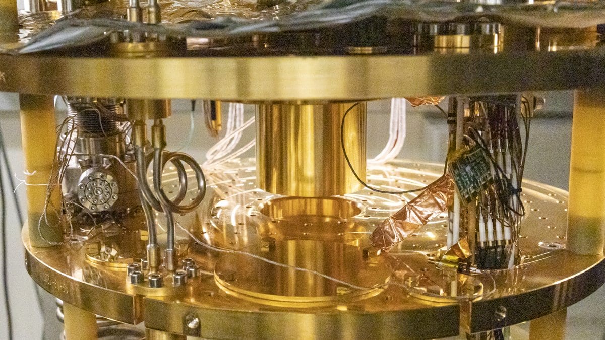 Gold-plated cold stages and coaxial microwave wiring inside an open dilution refrigerator in a quantum computing laboratory.