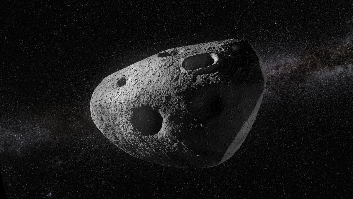 A visualization of a gray, heavily cratered asteroid lit from the left against a dense starfield.