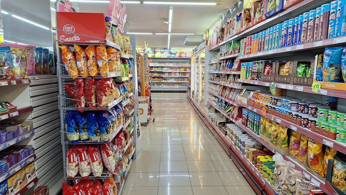 A supermarket aisle lined with shelves of packaged snack foods in bags and boxes.