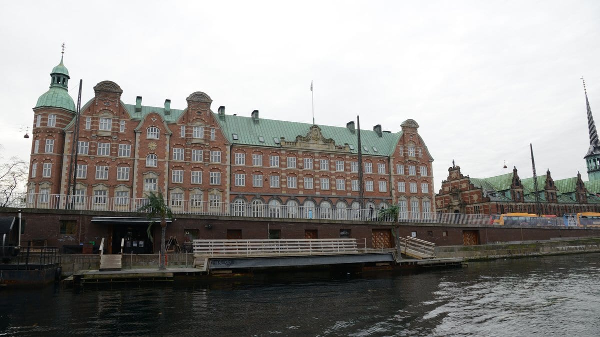 A red brick government building with a green copper roof on the Copenhagen waterfront, home to the Danish ministry responsible for the Central Person Register.