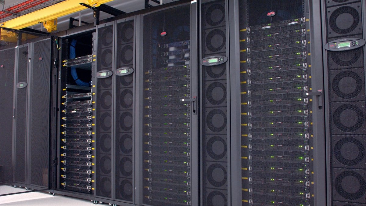 Rows of black server cabinets holding graphics-processor nodes in a data center, green status lights along each unit.
