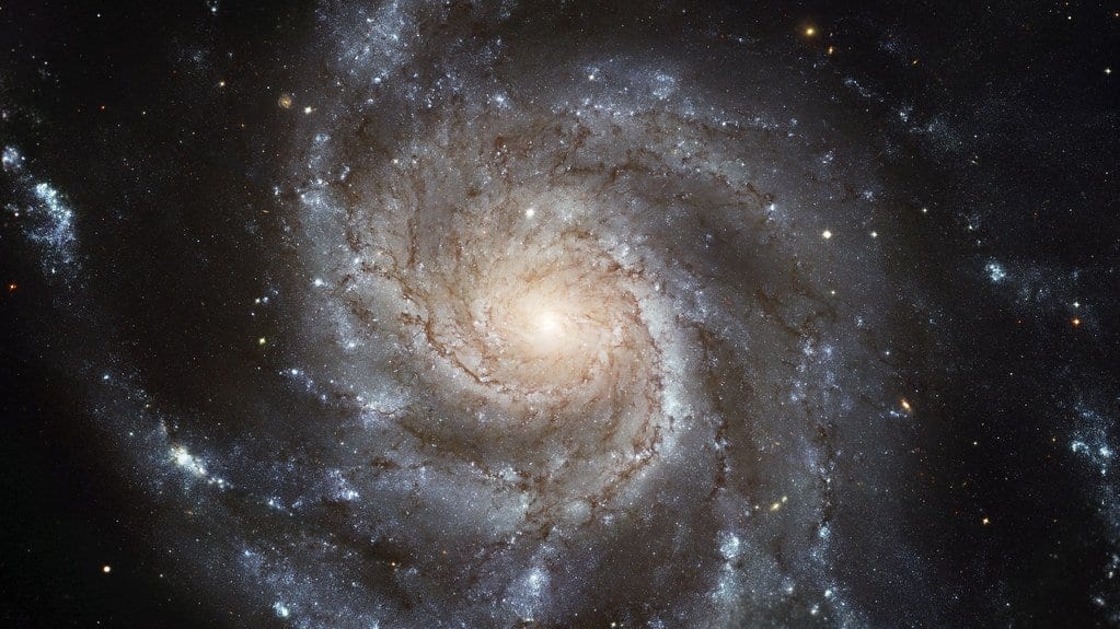 Hubble image of the spiral galaxy Messier 101 seen face on, with blue spiral arms winding out from a bright core.