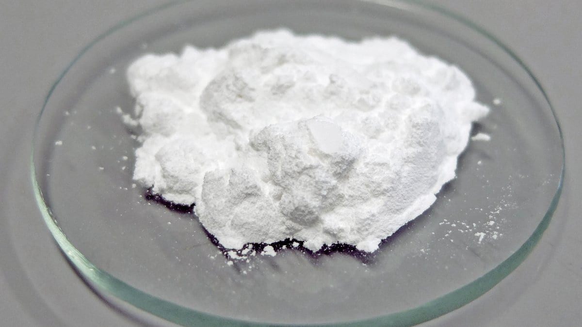 A mound of fine white lanthanum oxide powder resting in a round glass dish.