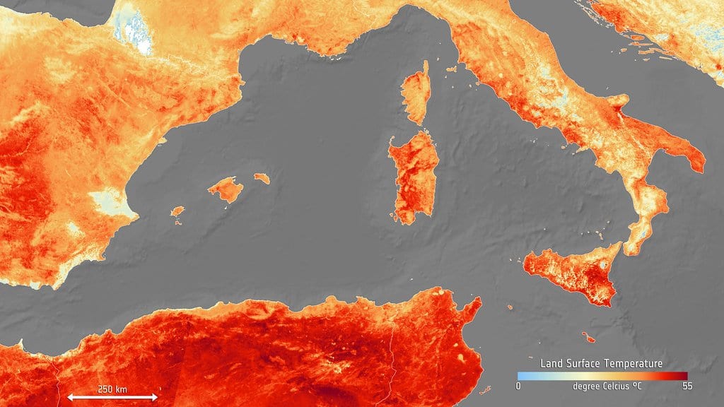 A satellite map of land surface temperature over Spain, southern France, Italy and North Africa, shaded pale yellow through deep red over the hottest ground, with the sea in gray.