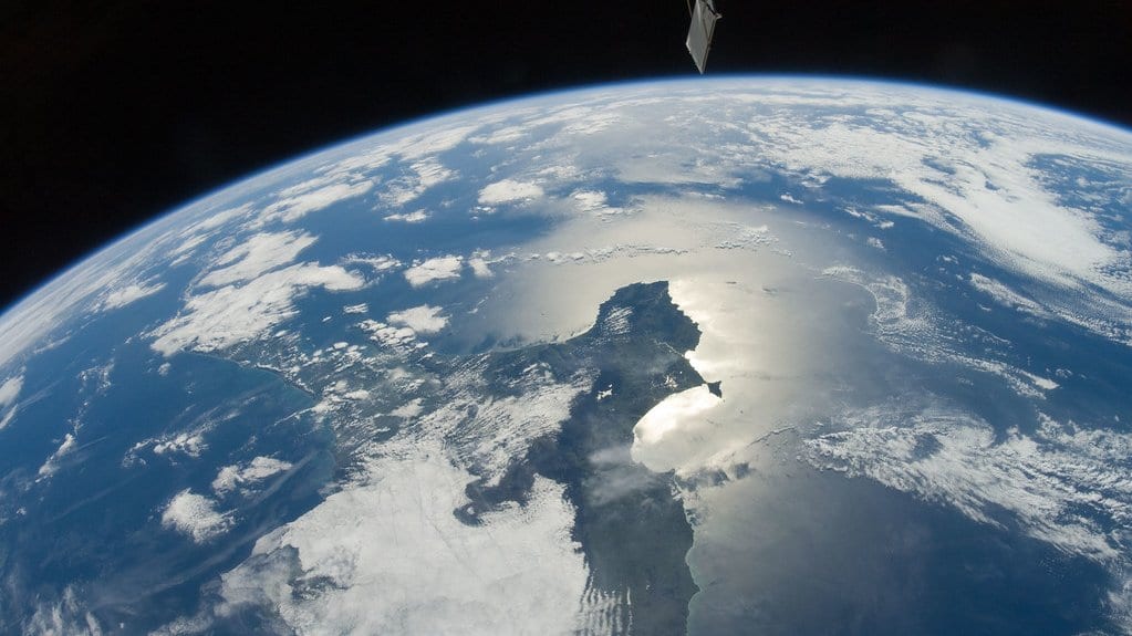 Oblique photograph from the International Space Station showing the Azuero Peninsula on Panama's Pacific coast, with sunlight glinting off the sea and scattered clouds over the land.