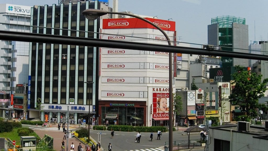 A multistory building in a Japanese city carries Big Echo karaoke signs on several floors, seen from across a street crossing.