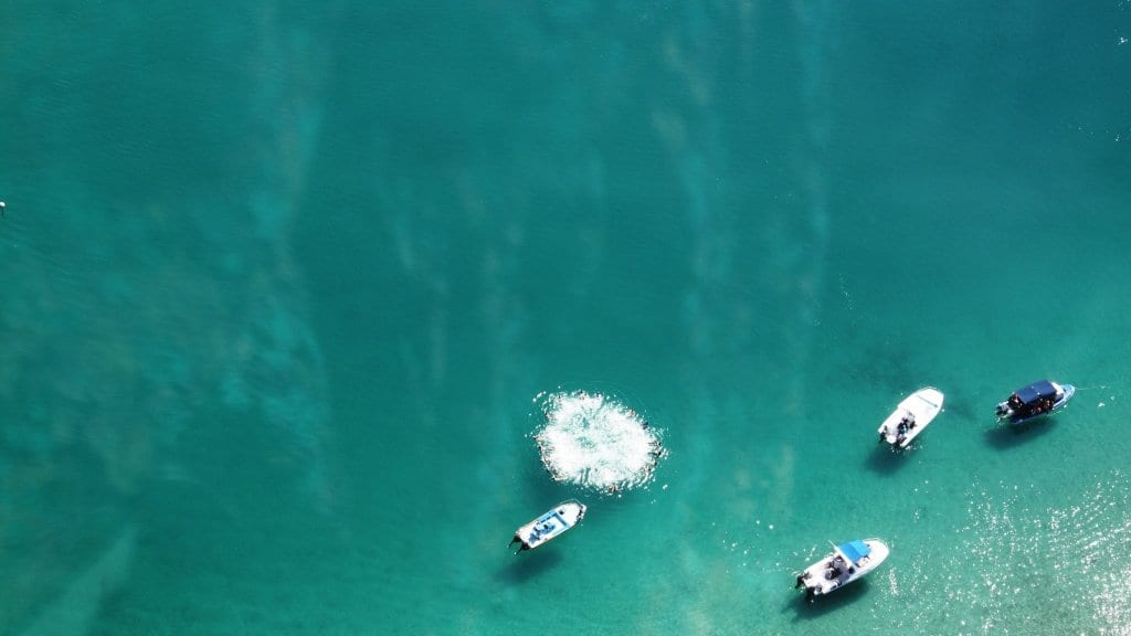 Aerial view of shallow turquoise water over a patchy seabed in the Bazaruto Archipelago, Mozambique, with small boats at anchor.