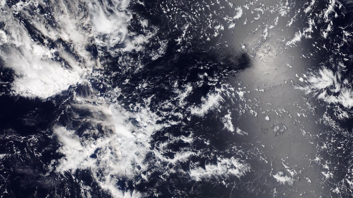 Satellite view of scattered clouds over open ocean in the equatorial Pacific, with sunlight glinting off the water