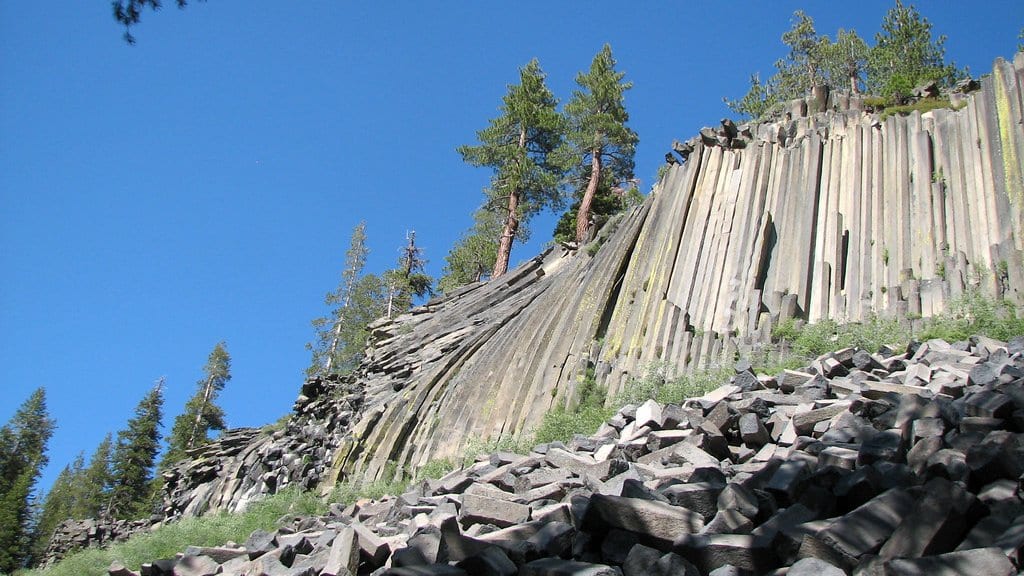A cliff of tall basalt columns seen from below, with a slope of broken column fragments beneath it