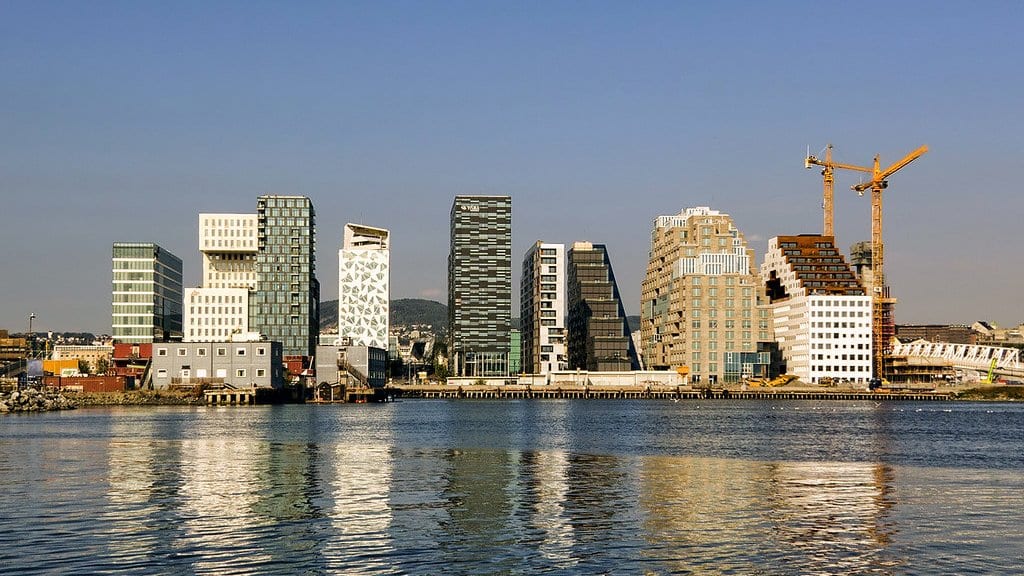 Modern high rise office towers along the Bjorvika waterfront in Oslo, Norway, reflected in the water of the fjord.