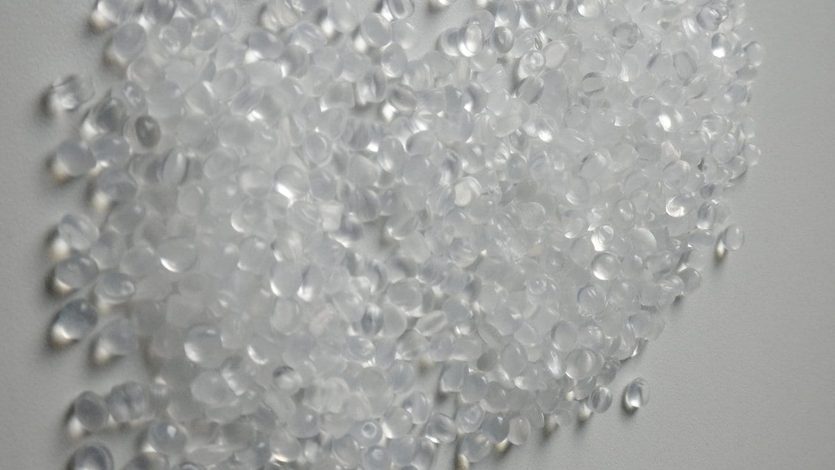A heap of small translucent polyethylene pellets on a gray surface.