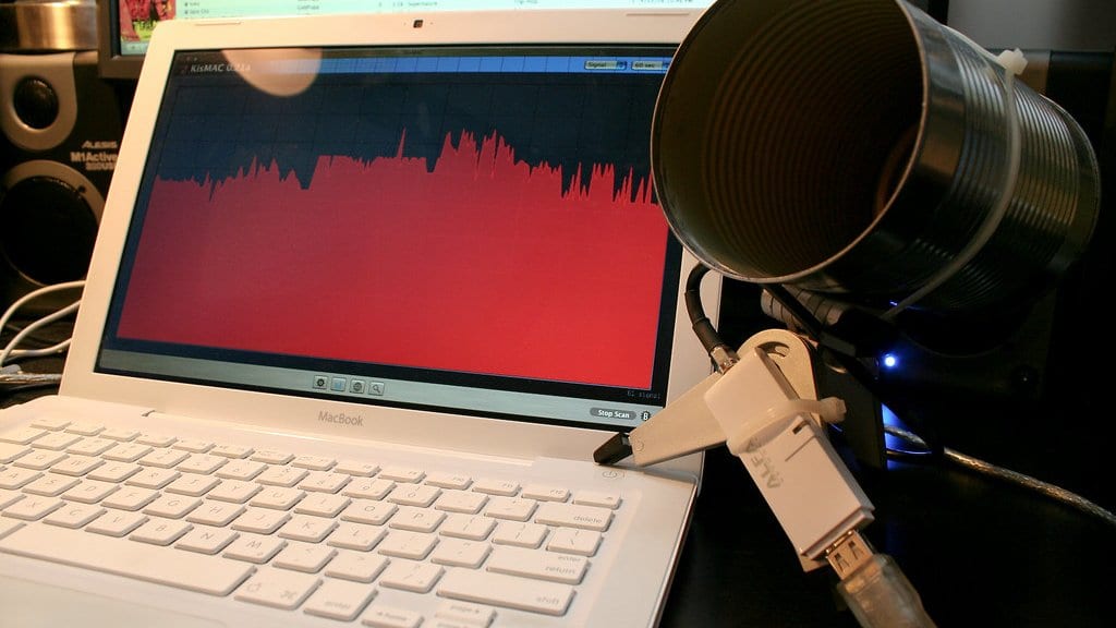A tin can mounted as a directional antenna beside a laptop screen showing a live scan of nearby wireless signals.