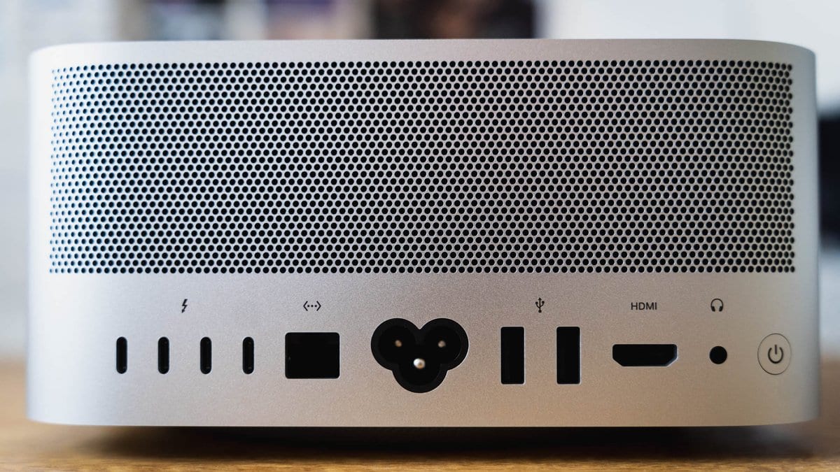The rear panel of a silver Mac Studio desktop computer, with a row of Thunderbolt, USB, HDMI and headphone ports below a circular perforated cooling grille.