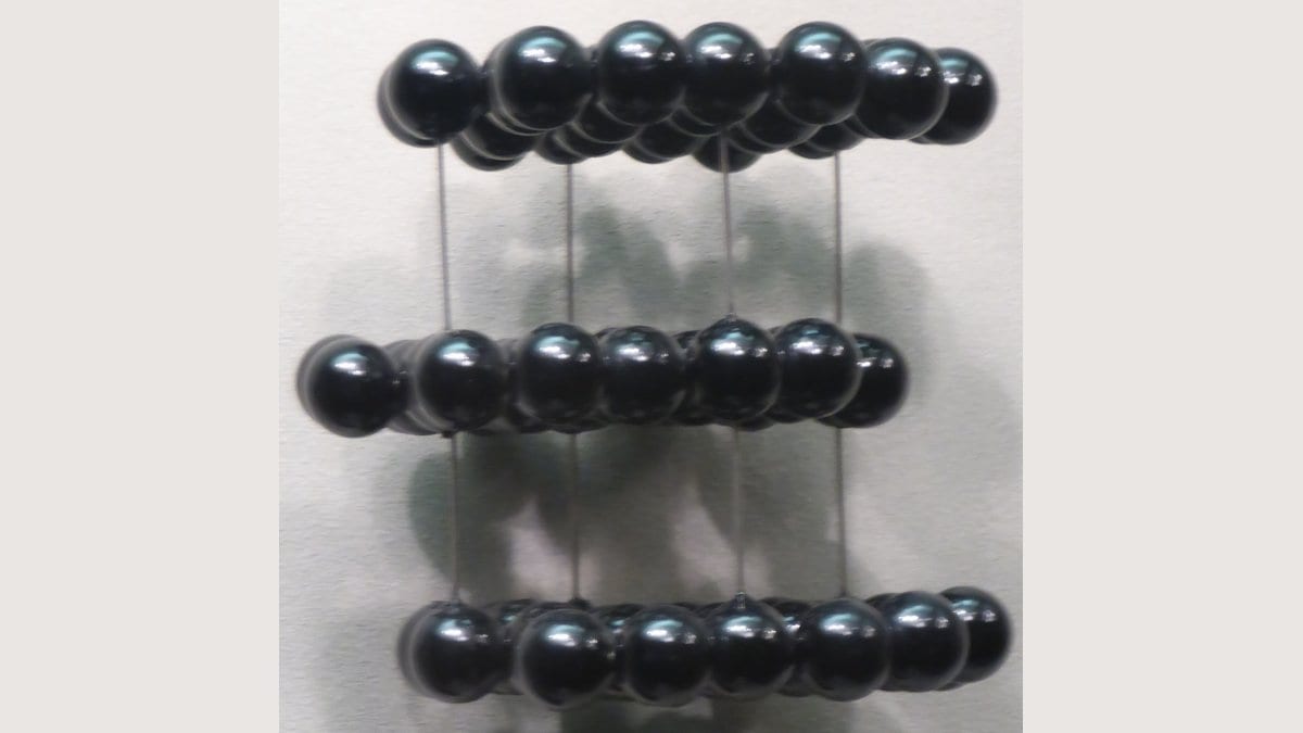 A ball and stick model of graphite showing three parallel sheets of carbon atoms, each sheet separated from the next by an open gap.