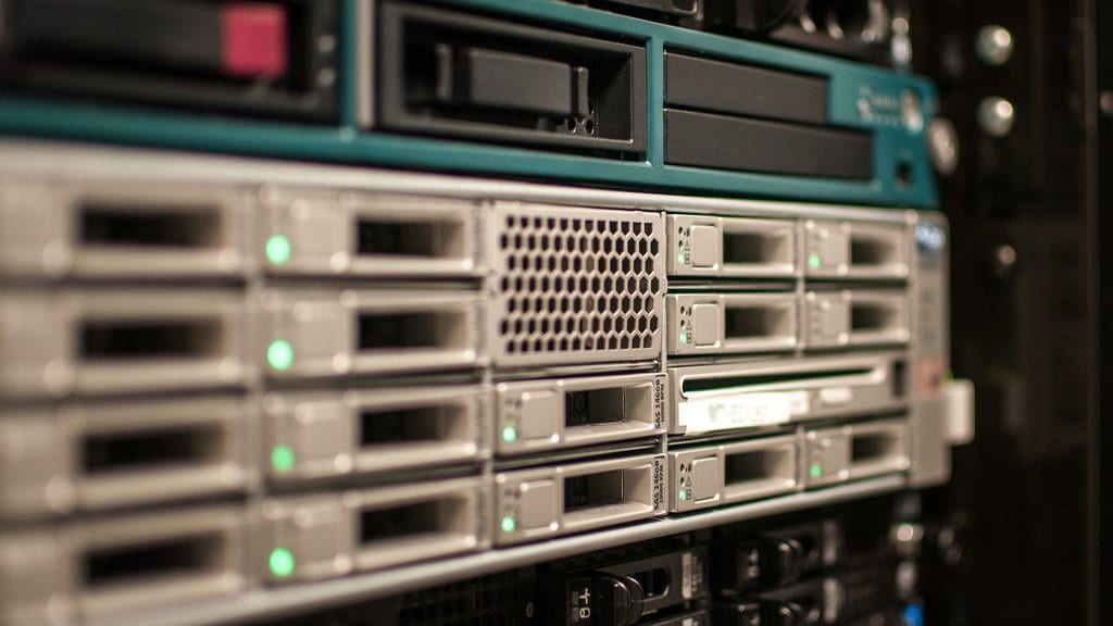 Close view of rack mounted servers in a data center, with rows of drive bays and green status lights.
