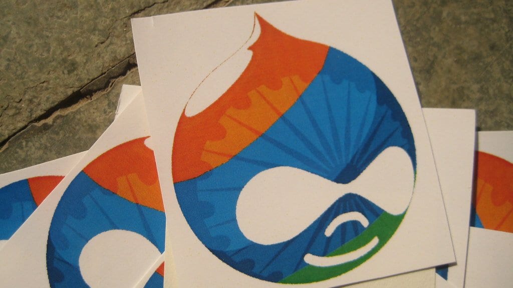 Sheets of stickers printed with the Drupal droplet mascot, lying on a stone surface.