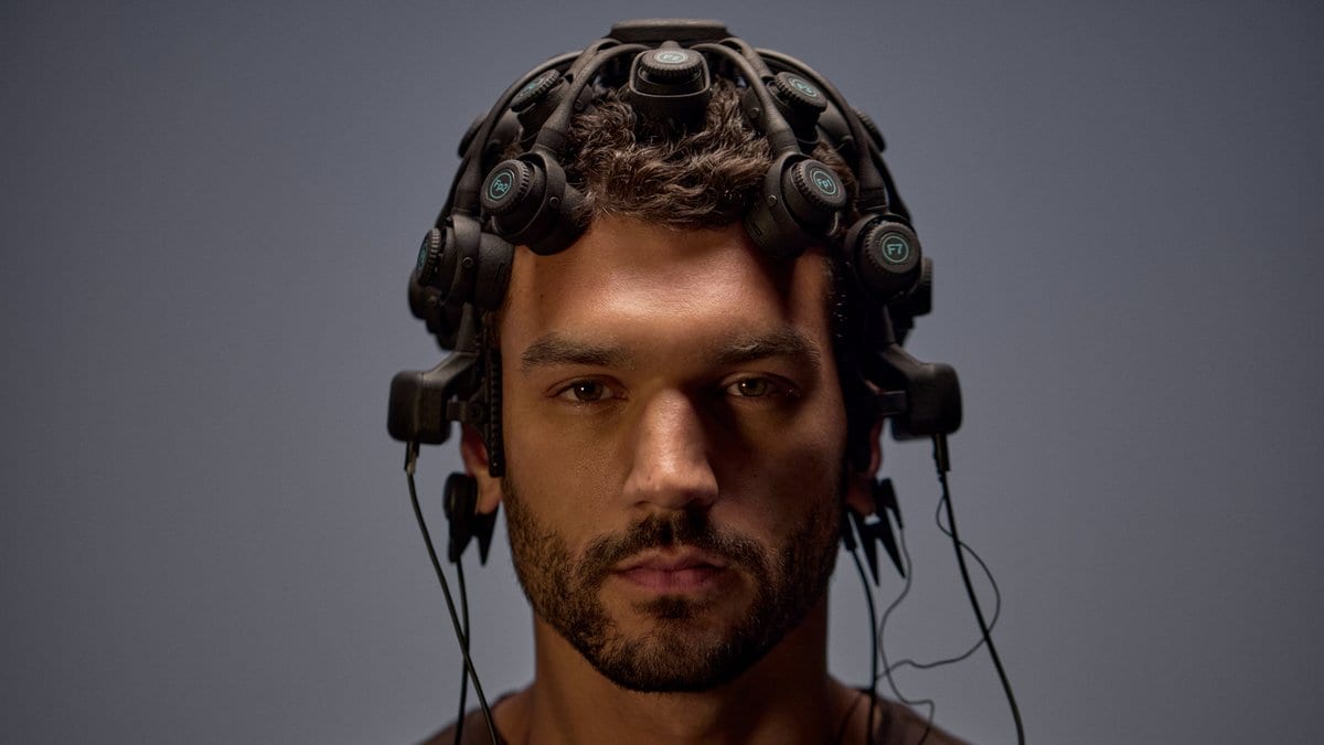 A man wearing a dry-electrode EEG headset, with cables running from sensors pressed against his scalp.