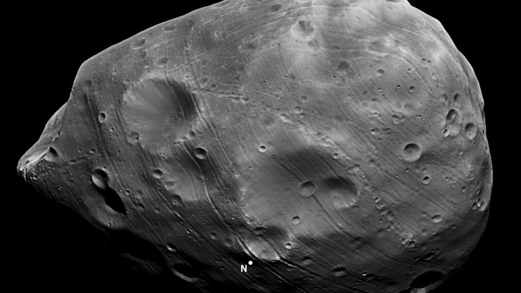 The irregular, heavily cratered moon Phobos against black space, grooves running across its surface and a large crater on its left side.