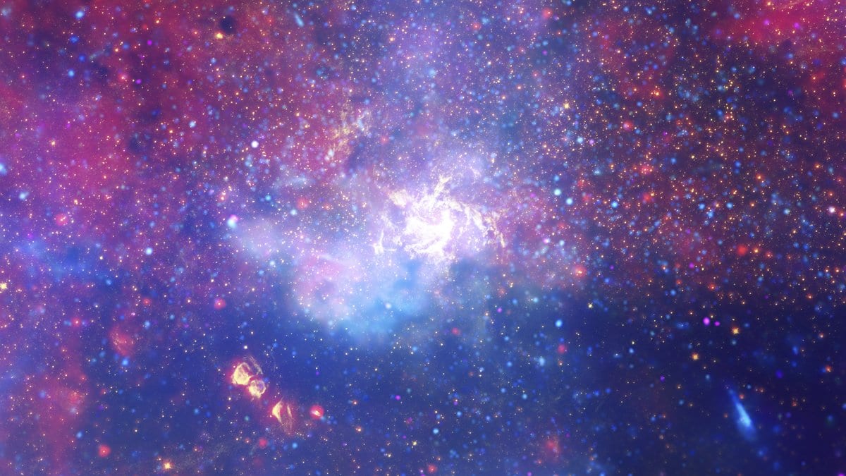 A crowded field of stars and glowing pink and blue gas filling the frame, brightest at a white knot in the middle.