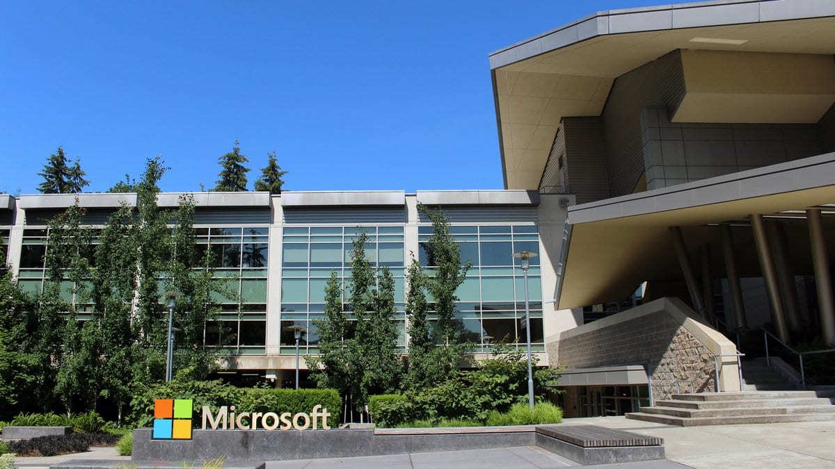 Building 92 on Microsoft's campus in Redmond, Washington, with the Microsoft name and four-color logo on a low stone sign in front of the glass office block.