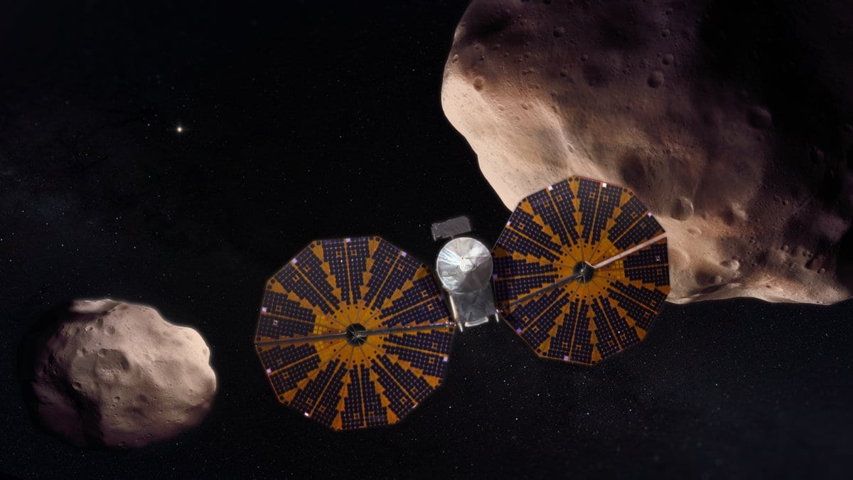 Artist's rendering of NASA's Lucy spacecraft, its two round solar arrays extended, passing between two dark, cratered asteroids in deep space.
