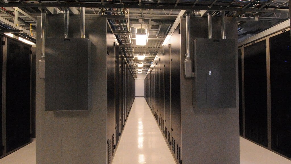 A corridor between two rows of closed server cabinets inside a data center.