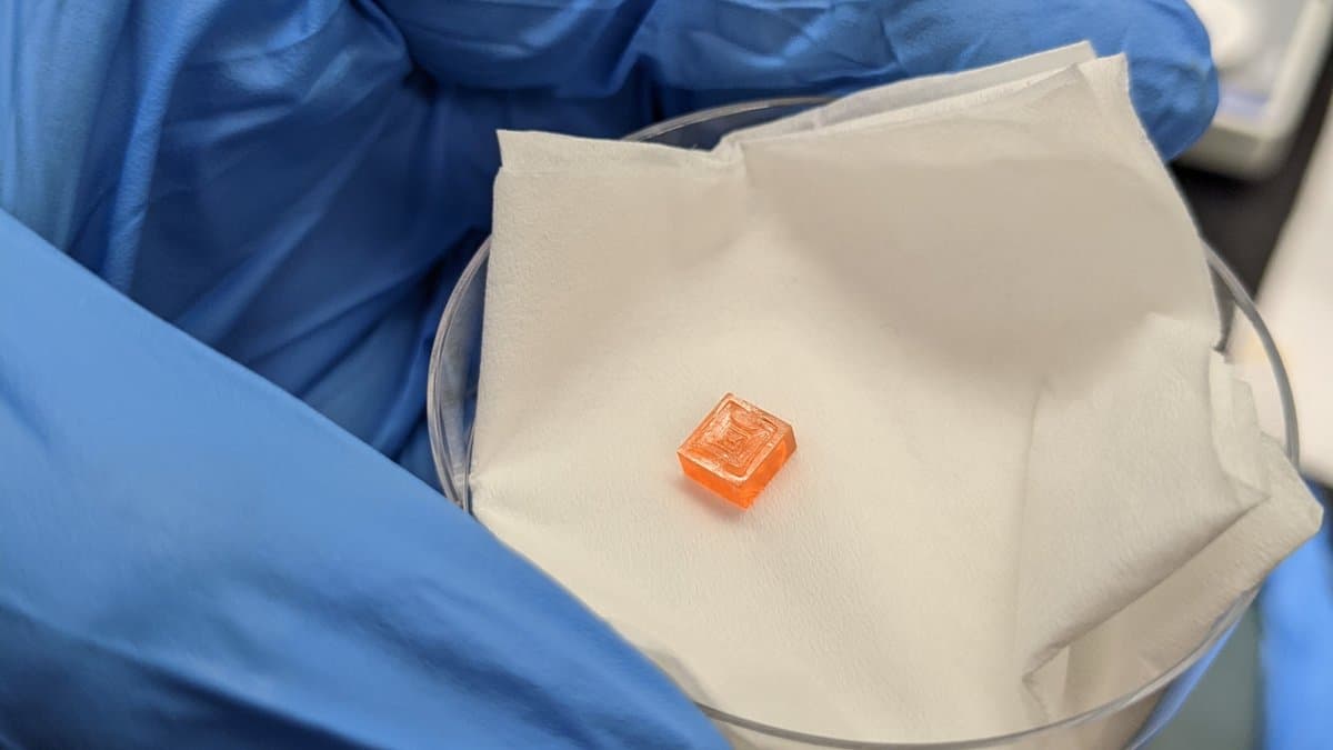 An orange, rectangular solution-grown perovskite crystal sitting in a Petri dish