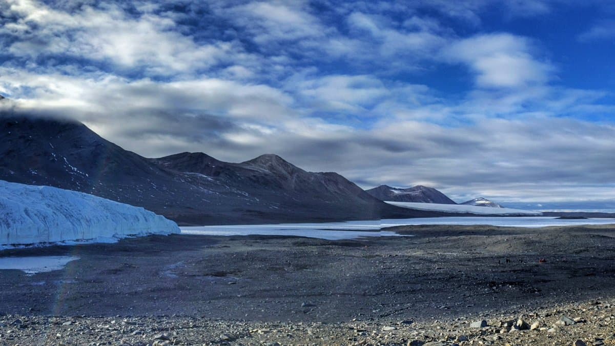 Bare, ice-free gravel valley floor in Taylor Valley, one of the McMurdo Dry Valleys in Antarctica, flanked by dark mountain slopes