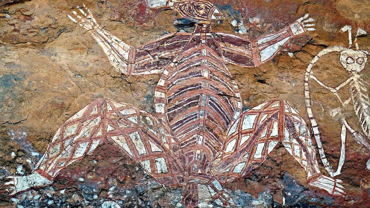 Aboriginal rock painting of a large ancestral figure in X-ray style, pale bones and joints outlined in white and red on the rock face of a sandstone shelter.