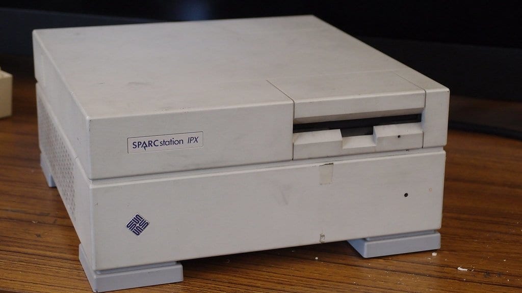A beige desktop Unix workstation with a model badge on its front panel, sitting on a wooden desk.