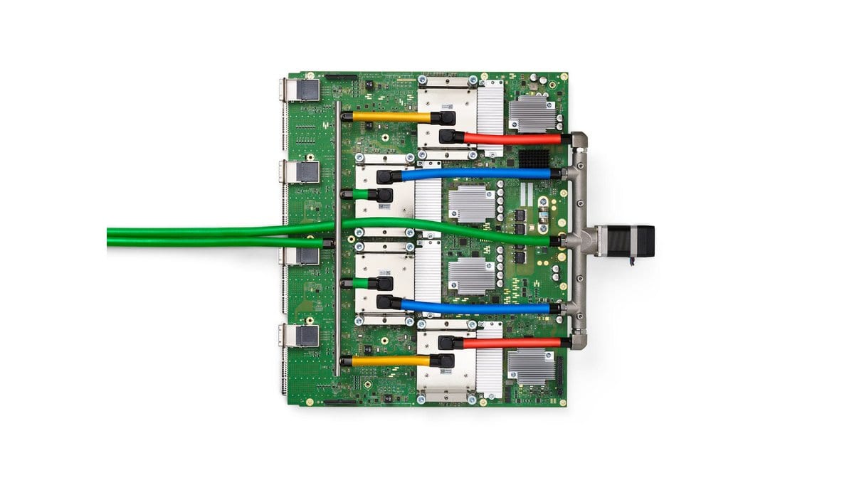 A Google TPU v4 board seen from above, with four accelerator chips under metal heat sinks, colored cables and optical connectors on a white background.